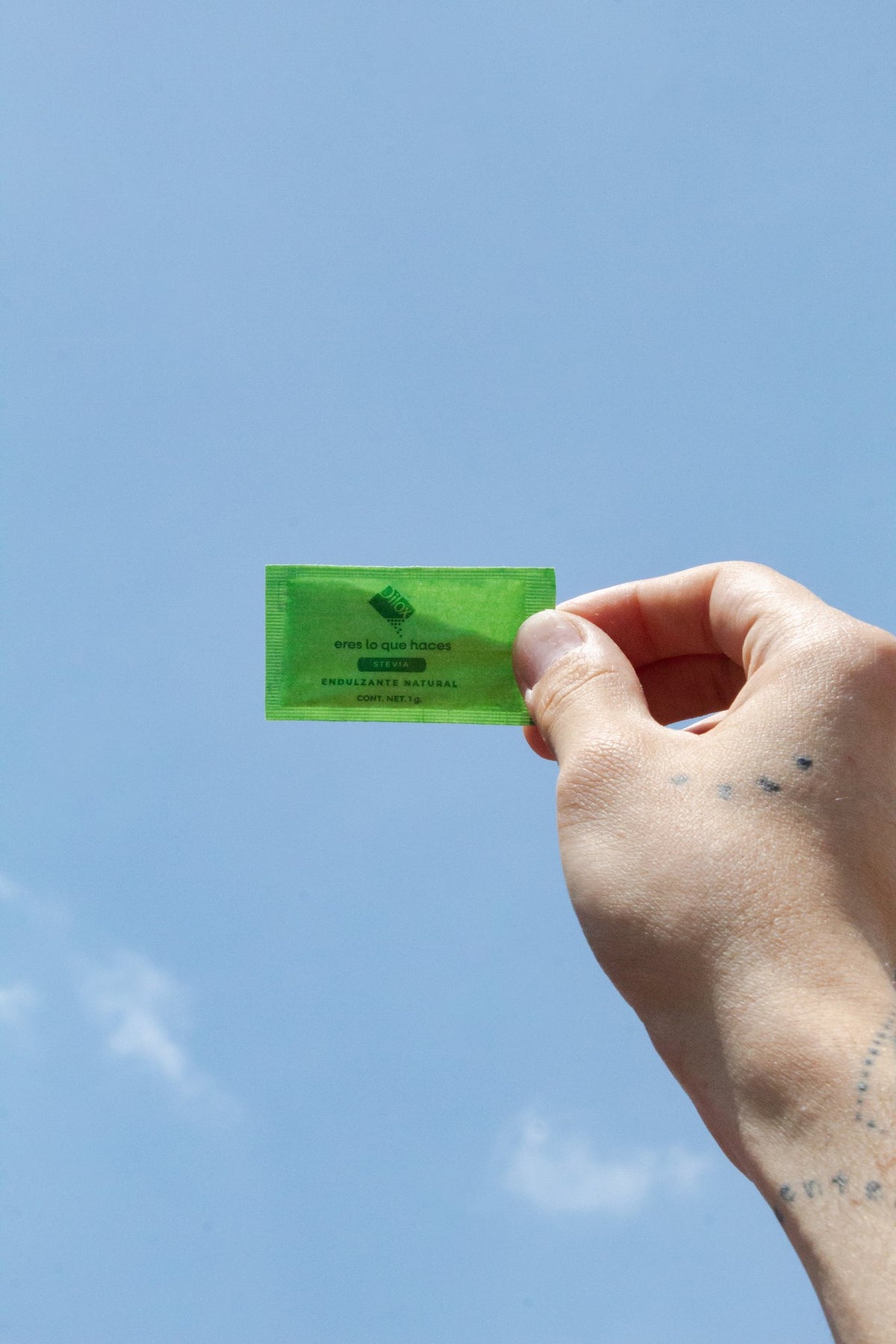 Sobre de stevia Dilox en mano con cielo azul